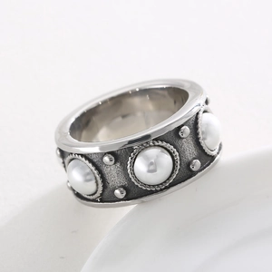 Détail d'une bague vintage en acier inoxydable avec incrustation de perles et finition argent