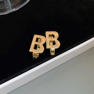 Macro shot of gold-plated double B letter earrings with high-polish mirror finish