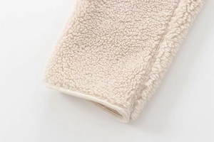 Macro shot of soft off-white sherpa fleece fabric texture and premium seam detail