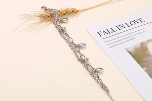 Detail eines silbernen mehrlagigen Kettenarmbands mit ovalem Anhänger und Verschluss
