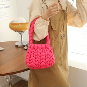 Close-up of bright pink hand-knitted tote bag showing thick wool texture and handle