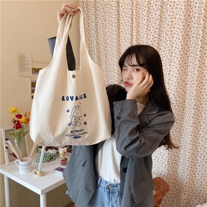 Détail du sac cabas en toile blanc cassé avec imprimé dessin animé bleu et bouton pression