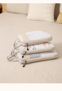 Close-up of beige compression travel organizer set with mesh panels on a bed