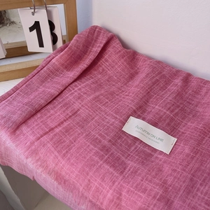 Detail of pink cotton linen scarf featuring a woven grid texture and brand fabric label
