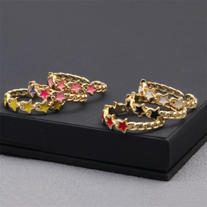 Macro detail of five 18K gold-plated star rings with colorful enamel finishes in a box