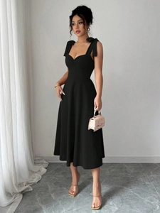 Detail van een elegante zwarte midi-jurk met schouderstrikken en hartvormige halslijn