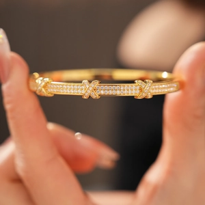 Macro view of 18k gold plated X-shaped clasp bracelet with pavé cubic zirconia