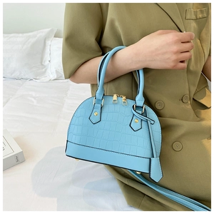 Detail of light blue croc-embossed mini dome bag with gold hardware and top handles