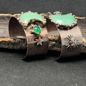 Detail eines Vintage-Kupferarmbands mit grünem Edelstein, Mond-, Sonnen- und Sternenmotiven