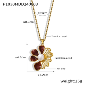 Dettaglio della collana con ciondolo a fiore, petali rossi e perla su catena dorata