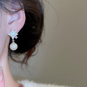 Vue détaillée de boucles d'oreilles étoile en perles plaquées or portées par un mannequin