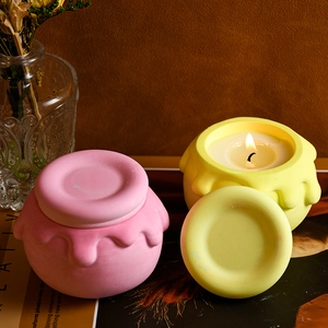Dettaglio candele a vasetto di miele rosa e gialle con design di cera colata