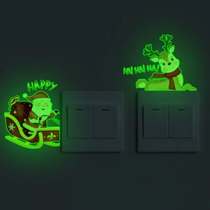 Luminous Santa and reindeer light switch stickers glowing green in a dark room