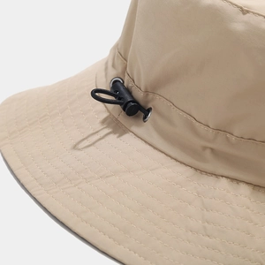 Detail of adjustable drawstring toggle and reinforced stitching on beige sun hat