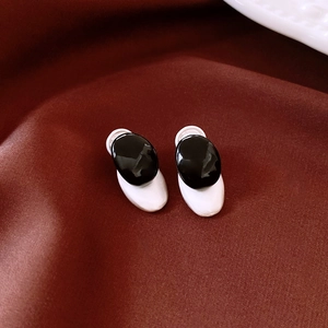Detailed view of monochrome contrast oval earrings on deep red elegant satin fabric