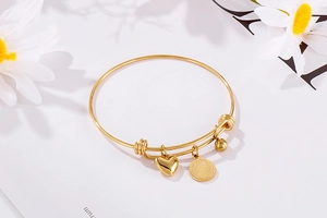 Detail view of gold heart and coin charms on a minimalist steel beaded bracelet