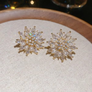 Detailed close-up of 18k gold flower earrings with marquise zircons and pearls