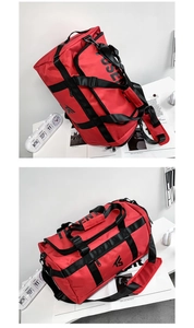 Detail of red oxford travel bag with black nylon straps and branding on white desk