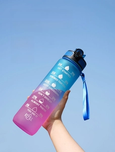 Detail of 32oz gradient water bottle with time markers and strap against a clear blue sky