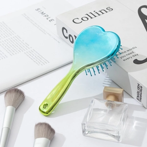 Detail of a heart-shaped hair brush in gradient blue-green finish on a styled desk
