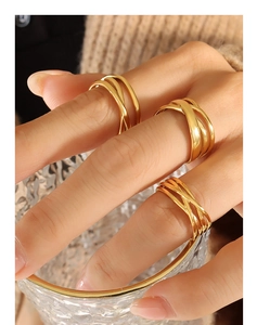 Close-up of three layered gold-plated geometric rings worn with textured glass