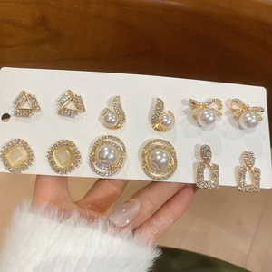 Detail of 6 pairs gold stud earrings set featuring pearls, rhinestones and cat eye stones