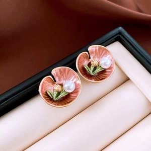 Detailed close-up of pink lotus leaf earrings with pearl centers in a velvet box