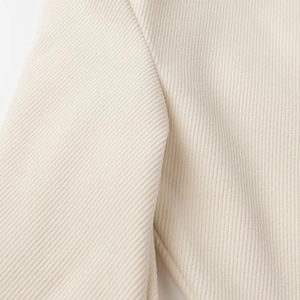 Dettaglio ravvicinato della trama in velluto beige e cuciture sotto l'ascella del cappotto