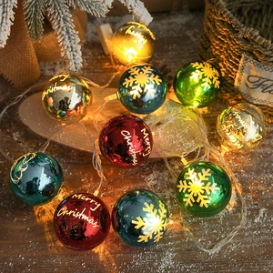 Colorful LED Christmas ball string lights with Merry Christmas prints on wooden surface