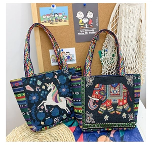 Detailed close-up of ethnic embroidered tote bag with geometric woven handle and folk patterns