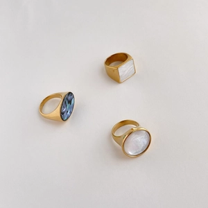 Detailed view of three gold rings featuring oval abalone shell and white mother of pearl
