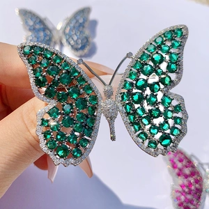 Macro shot of high-end butterfly brooch featuring vibrant green zirconia and silver plating