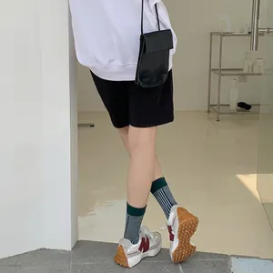 Minimalist green and black striped crew socks styled with black crossbody leather bag