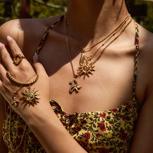 Close-up of gold layered necklace with seahorse and sun charms worn by a model