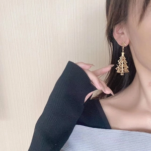 Close-up of golden Christmas tree earrings with star stud on model's ear