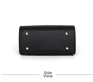 Detailed bottom view of a black leather handbag featuring four golden metal protective feet