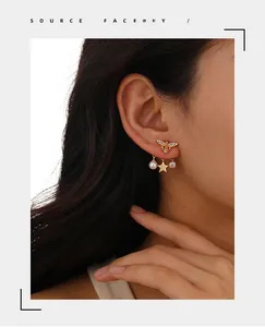 Close-up of luxury gold bee earrings with pearls, zircon stars, and crystal details