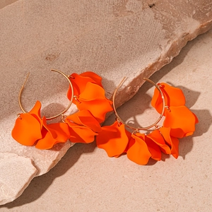 Detailed close-up of orange matte petal earrings on natural stone background