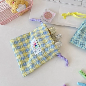 Gros plan d'une pochette à cordon à carreaux colorée pour produits de beauté et voyage