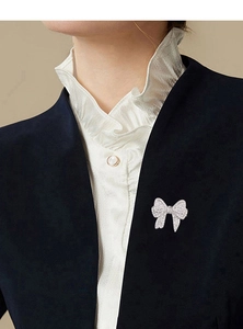 Detailed view of an elegant bow brooch with sparkling zircons pinned on a dark suit blazer