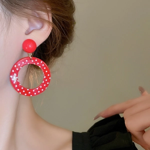 Close-up of a model wearing retro red resin hoop earrings with white polka dots pattern