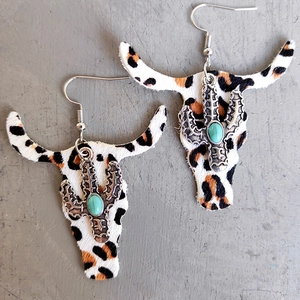 Detail of leopard print bull skull earrings with turquoise and silver cactus accent