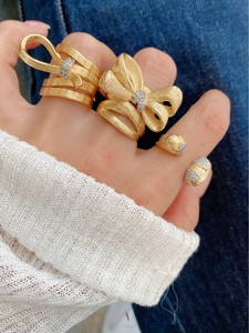 Detail of 18K gold bow ring with brushed texture and sparkling zircon inlay
