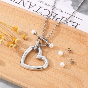 Vue détaillée du collier pendentif cœur argenté et boucles d'oreilles perles sur bois