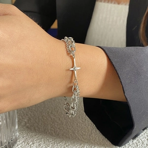 Detail of silver double chain bracelet with a star pendant on wrist with black blazer