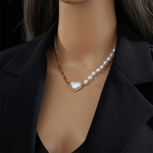 Asymmetric gold link chain and white pearl necklace with heart pendant on a model