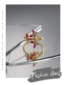 Close-up of golden butterfly ring with marquise-cut red stones and white zircons