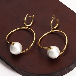 18K gold plated geometric dangle earrings with white brushed sphere on dark wood stand