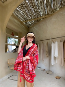 Detailed close-up of a large red ethnic shawl with geometric patterns and fringe tassels