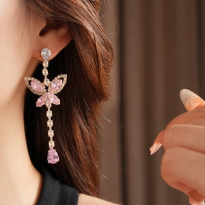 Close-up of pink butterfly drop earrings with cubic zirconia on a model's ear